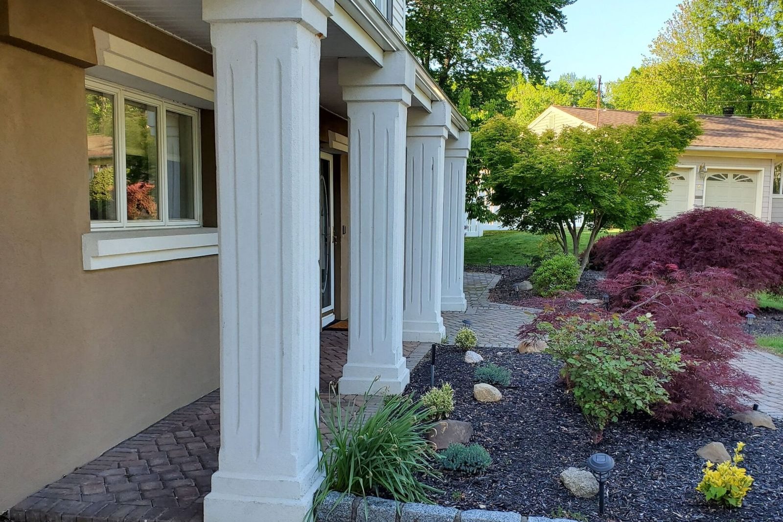 A finished home exterior with porch columns and new planting