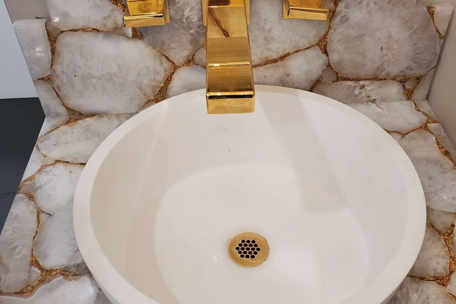 A remodelled bathroom with a stone vanity and gold fixtures