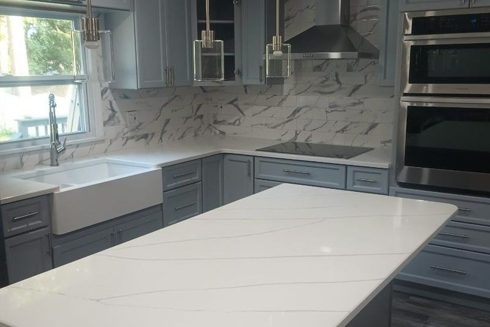 A finished kitchen with a stone-topped island and pendant lights