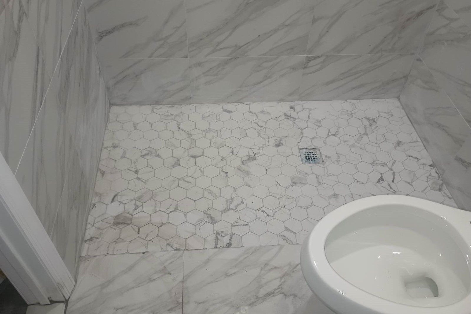 A marble-tiled shower and floor in a finished bathroom