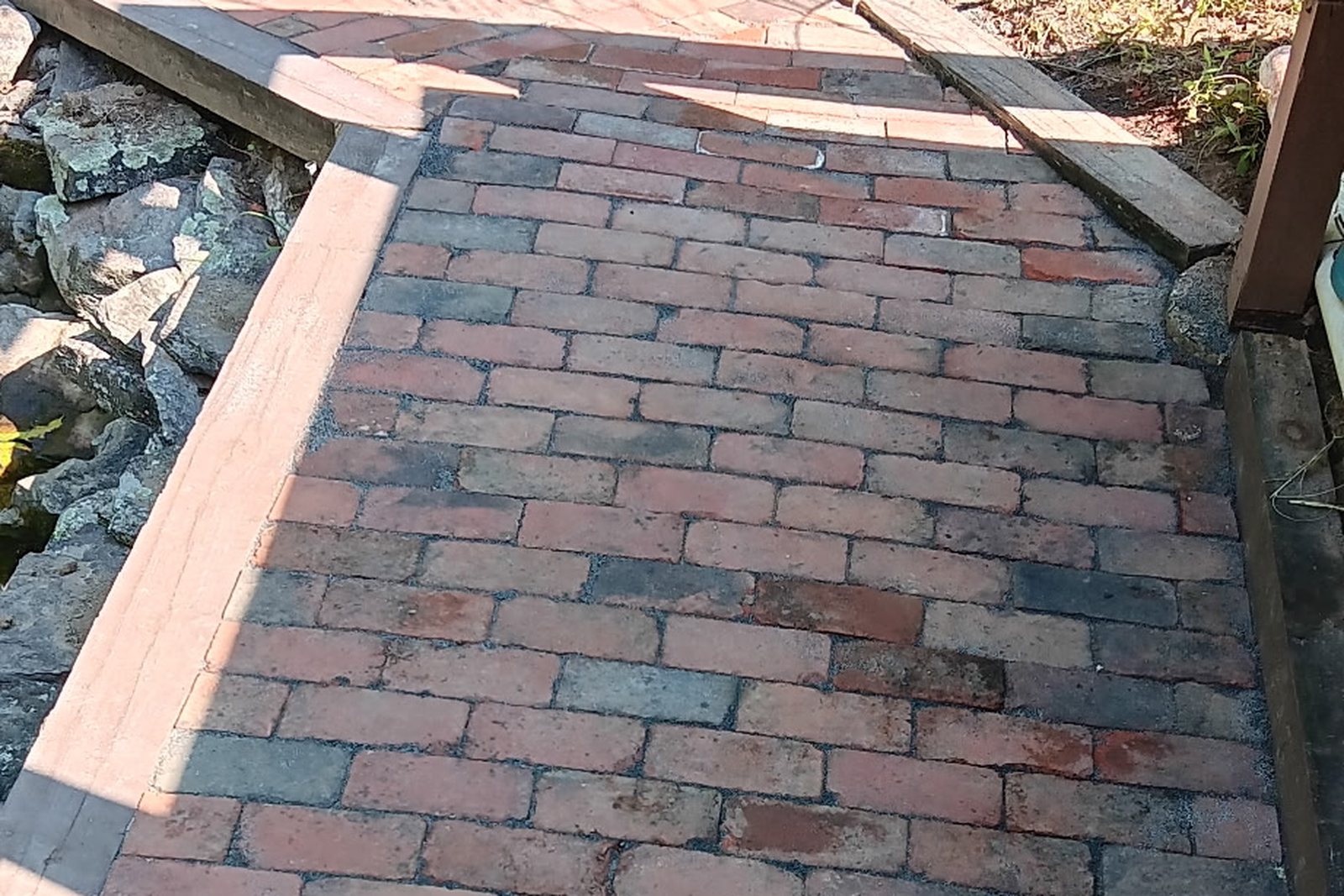 A finished brick paver path running between planted beds